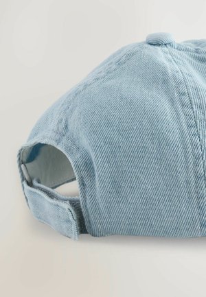 Helleblaue Denim-Cap mit runder Krone, sichtbaren Nähten und verstellbarem Riemen. Die Textur ist weich mit einem dezenten Rippmuster.