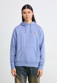 Light blue hoodie made of soft fabric, featuring a front pocket, adjustable drawstring hood, and a small logo on the chest.