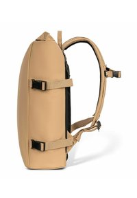 Mochila beige con correas ajustables de hebilla dobles en los laterales y correas de hombro acolchadas, mostrada de lado sobre un fondo blanco.
