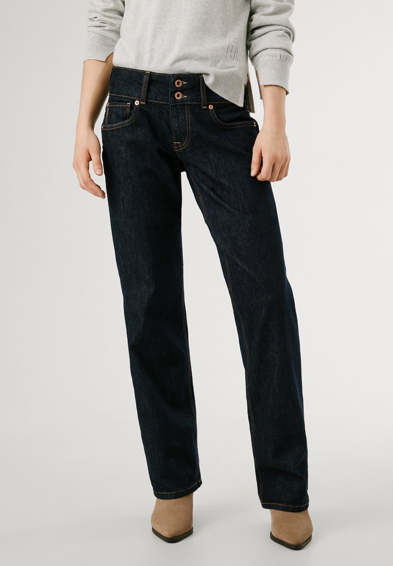 Temno modri kavbojke ravnega kroja, ki imajo dvojno gumbno zapiranje, sprednje žepke in oranžne šive.