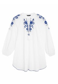 Camicia di cotone bianca con ricamo floreale blu, collo con cordoncino e maniche lunghe e ampie. Presenta nappine decorative e dettagli al fondo.