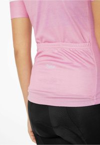 Ružová športová košeľa s krátkymi rukávmi, s rovnomerne zúženým pásom a jemným brandingom pri leme. Doplnkové čierne legíny s textúrou.