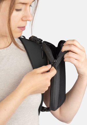 Black shoulder bag with a zippered pocket, made of textured fabric; features adjustable straps and a side buckle for secure closure.