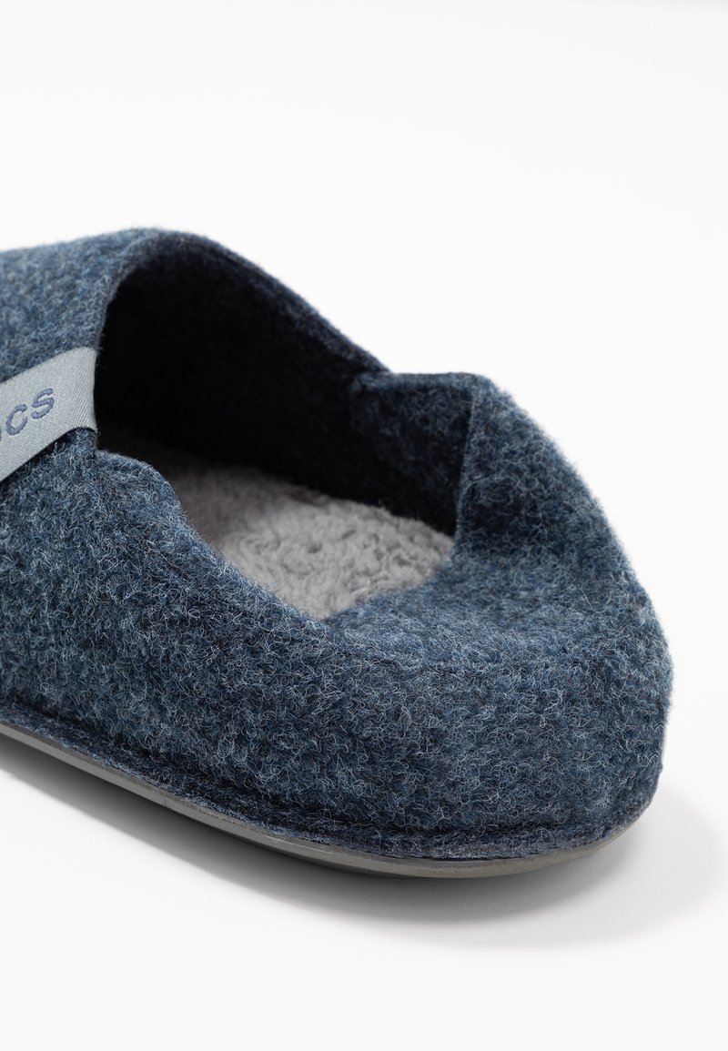 Zapato sin cordones de fieltro azul oscuro con un suave forro interior gris y una textura exterior sutil. Presenta una etiqueta gris clara con la palabra "CS".