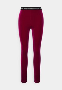 Åtsittande, sammetslena bourgogne leggings med svart elastisk midja som har vit logotyp-text. Slät yta och design som når ankeln.