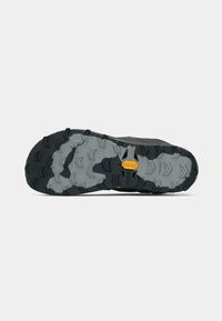 Black and grey trail shoe outsole with a prominent grip pattern and a yellow logo. Textured rubber offers traction for various terrains.