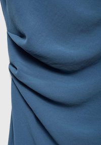 Texturiertes blaues Gewebe mit weichen Falten, das eine glatte Oberfläche und ein mittleres Gewicht aufweist, ideal für verschiedene Bekleidungsanwendungen.