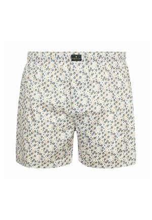 White boxer shorts with small blue and yellow floral pattern and elastic waistband with a black brand label at the front center.
