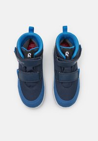 Modré vysoké tenisky vyrobené z textilu a semiše, s suchými zipy, kontrastní světlomodrou vnitřní podšívkou a bílou gumovou podrážkou.