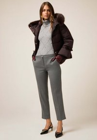 Chaqueta acolchada de color marrón oscuro con capucha forrada de piel, suéter gris con patrón de diamantes, pantalones grises a medida y zapatos negros de tacón.