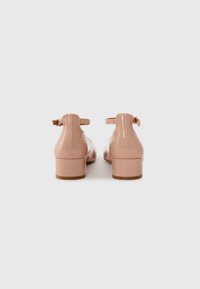 Pink patent leather shoes with a low block heel, featuring adjustable ankle straps and a smooth, glossy texture.