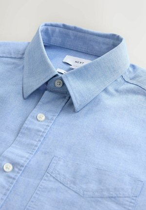 Svetlo modra srajca s gumbi in širšim ovratnikom, eno prsno žepom in kontrastnimi belimi gumbi. Narejena iz mehkega, teksturiranega materiala.