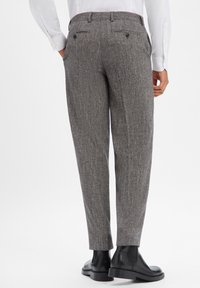 Szare spodnie o wzorze jodełki, dopasowane, z tylnymi kieszeniami i gładką teksturą, zestawione z czarnymi botkami za kostkę.