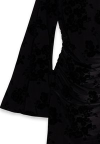 Črna obleka z dolgimi zvonastimi rokavi, mehkim žametnim materialom s tonalnim cvetličnim vzorcem in gubanjem na strani, ki zagotavlja oprijet videz.