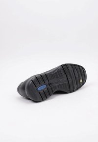 Sole di scarpa nera con pattern testurizzato, caratterizzata da un'etichetta blu per l'assorbimento degli urti e un'accenzione gialla, progettata per durata e aderenza.