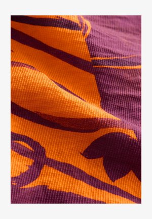 Mønstret tekstil med bølget design i orange og mørk lilla. Materialet har en tekstureret, ribbet overflade, der fremhæver farverne.