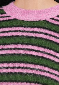 Πλεκτή μπλούζα με ρίγες σε ροζ, πράσινο και μαύρο. Μαλακή υφή, λαιμόκοψη λαιμόκοψη και αφράτο φινίρισμα. Εναλλασσόμενα μοτίβα ρίγας.