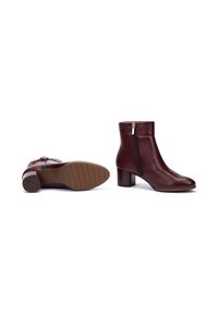 Botas de tobillo de cuero burdeos con cremallera lateral, puntera redondeada y tacón de bloque. Suela de goma texturizada con un sutil patrón de relieve.