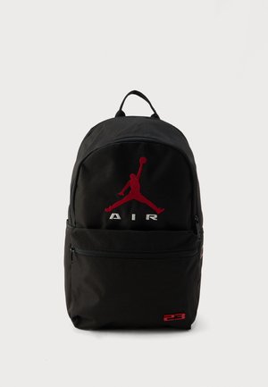 Juoda kuprinė iš patvarios medžiagos, ant kurios yra raudonas Jumpman logotipas ir baltos spalvos užrašas „AIR“. Yra priekinė kišenė su užtrauktuku ir viršutinė rankena.