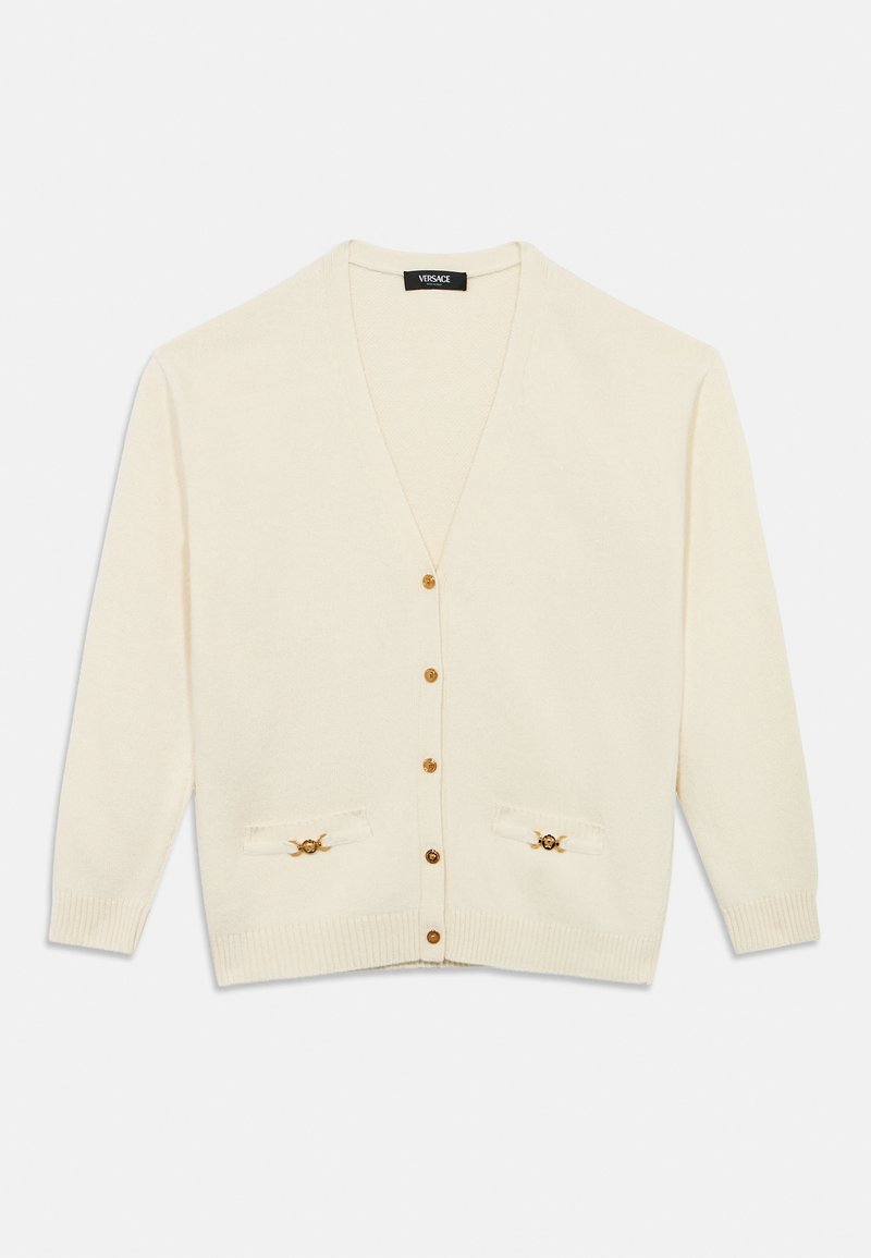 Κρεμ ζακέτα με V-λαιμόκοψη, κουμπιά μπροστά, ριμπ μανσέτες και δύο διακοσμητικές τσέπες με χρυσές λεπτομέρειες. Μαλακή υφή.