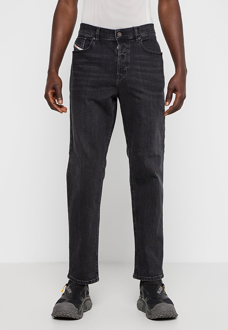 Jean en denim noir à coupe droite, avec cinq poches et une légère décoloration. Dispose d'une fermeture à bouton et de coutures détaillées sur la poche.