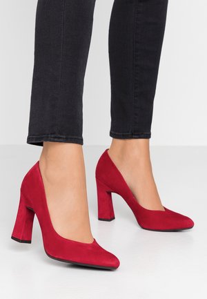 Røde ruskind høje hæle med rund tå og en mellemhøj blokhæle, der har en glat tekstur og en let hævet silhuet.