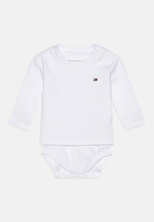 Białe body dla niemowląt z długim rękawem, z zatrzaskami na ramieniu i kroku, z małym prostokątnym logo w kolorach czerwonym, białym i niebieskim na piersi.