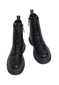 Stivali in pelle nera con gambale alto, allacciatura frontale e dettagli con zip; suola in gomma spessa con accenti di cucitura a contrasto.