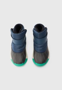 Ein Paar navyblaue und graue Winterstiefel mit grünen Sohlen, gepolstert für Wärme, von oben betrachtet auf einem weißen Hintergrund.