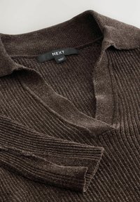 Brun ribbet fløjlstriktrøje med krave og lange ærmer, foldet pænt og viser NEXT mærkeskiltet.