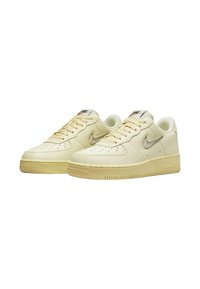 Sneakers Nike Air Force 1 color crema con tomaia in pelle texturizzata, punta rotonda, perforazioni per traspirabilità e suola in gomma.