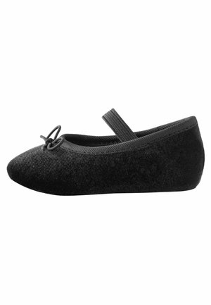 Chaussure plate Mary Jane en velours noir avec une fine bride élastique sur le cou-de-pied et un petit nœud décoratif à l'avant arrondi.
