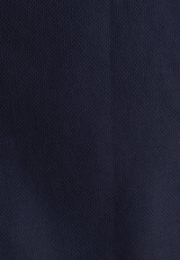 Tissu bleu foncé avec un tissage finement texturé, montrant des ombres subtiles et des plis à la surface.