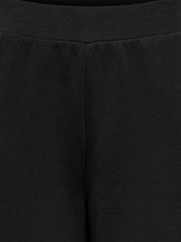 Close-up van zwarte rekbare leggingstof met zicht op tailleband en centrale naad.