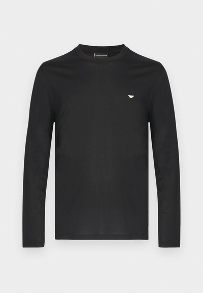 Fekete, hosszú ujjú pamut póló. Kerek nyakkivágással és egy kis arany logóval a bal mellrészen. Simogatott textúra, testhezálló szabás.