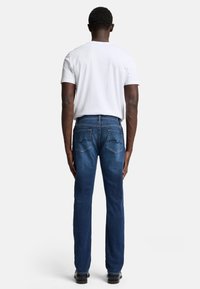 Menns blå denim jeans med rett ben, detaljert søm og to baklommer, kombinert med en enkel hvit t-skjorte.