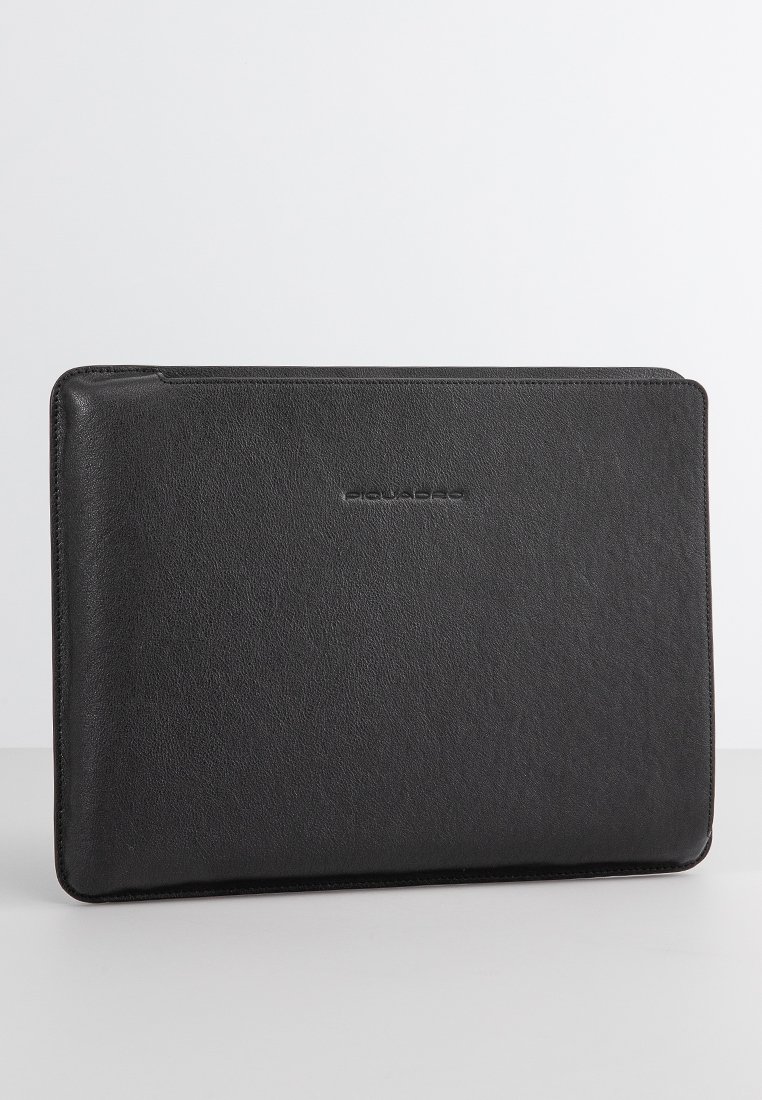 Schwarze Leder-Laptop-Hülle mit glatter Textur, rechteckiger Form und dezentem Branding. Verfügt über einen Reißverschluss entlang der oberen Kante.