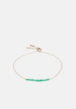 Delikatna bransoletka z łańcuszka ze złota z szeregiem małych zielonych koralików i regulowanym suwakiem na jednolitym białym tle.