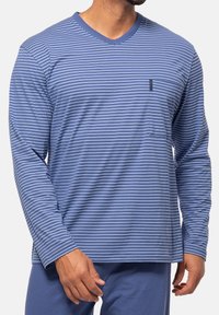 Pitkähihainen siniraitainen paita, jossa on V-kaulus ja pehmeä kangas. Paidassa on valkoisia vaakaraitoja ja yksi tasku rinnassa.