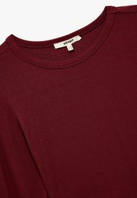 Bordeaux t-shirt met een ronde hals, gemaakt van zachte katoen. Beschikt over korte mouwen en een label op de hals.