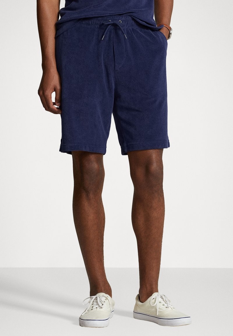 Marinblå frottéshorts med elastisk midja och snörning. Knälång design med avslappnad passform och mjuk yta.