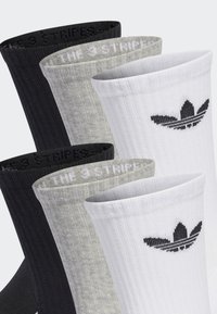 Vier Paare Crew-Socken in Schwarz, Grau und Weiß. Jede Socke hat eine gerippte Textur und ein kontrastierendes Logo oben.
