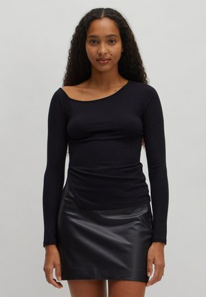 Zwarte geribbelde longsleeve top met een asymmetrische halslijn, gecombineerd met een zwart faux leren minirok met een gladde textuur.