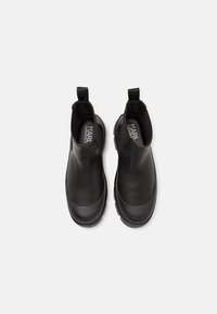 Botas negras de tobillo hechas de cuero suave, con paneles laterales elásticos, tiradores, punta redonda y una suela de goma texturizada.