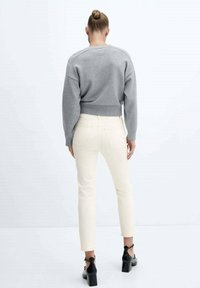 Šedá zkrácená mikina s žebrovaným pasem; zkombinováno se smetanovými skinny džíny a černými lodičkami, které ukazují minimalistický design.