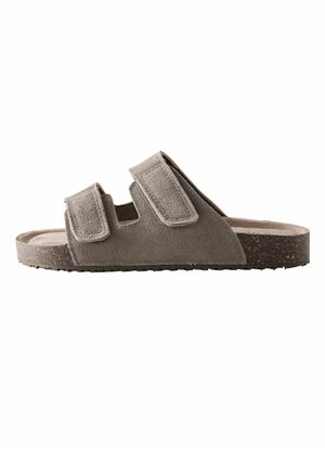 Grey suede slide sandal with two adjustable Velcro straps and a cork-textured sole, shown in side profile.