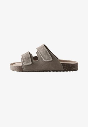 Sandalia tipo slide de ante gris con dos correas ajustables de velcro y suela con textura de corcho, mostrada en perfil lateral.