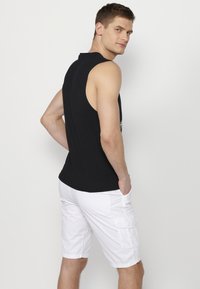 Must mustraga t-särk ümmarguse kaelusega, millele on lisatud valged cargo-lühikesed püksid küljetaskutega ja mugava istuvusega.