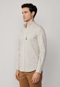 Camisa de hombre de manga larga y botón, hecha de tejido ligero con un patrón de cuadros multicolor en azul, amarillo y blanco.