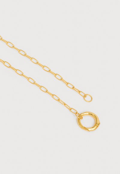 Χρυσό κολιέ αλυσίδα με επιμηκυμένους οβάλ κρίκους και μεγάλο κυκλικό κούμπωμα σε απλό λευκό φόντο.